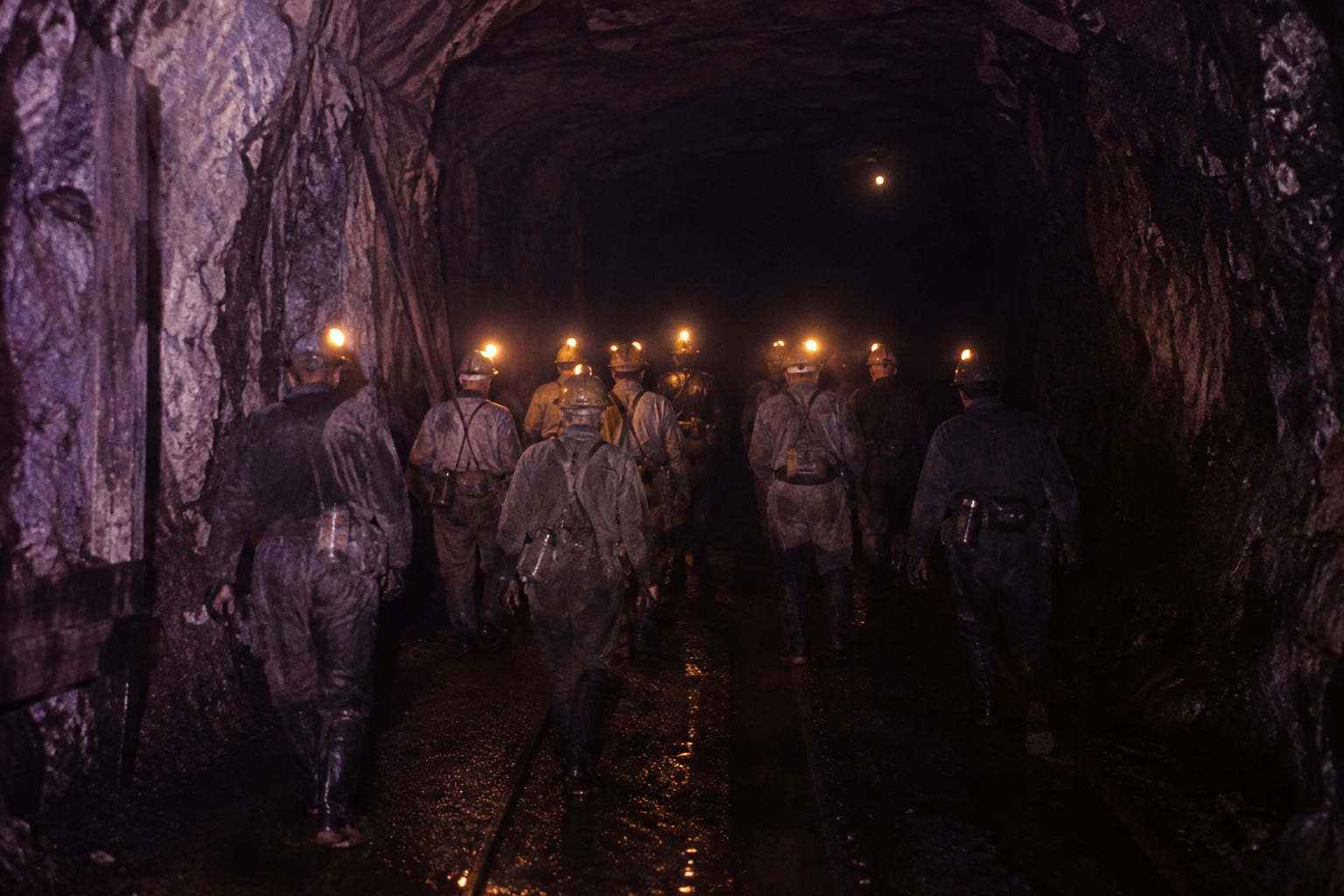 Miners' headlamps illuminate a deep coal tunnel